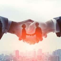 Business deal - two people shaking hands with a city in the background